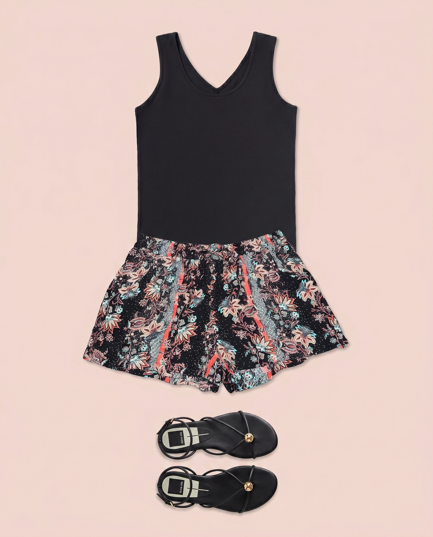 Black sleeveless top paired with floral print shorts on a beige background