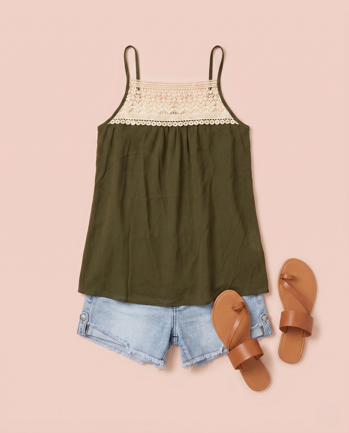 Olive green tank top with lace trim styled with denim shorts and sandals on a beige background