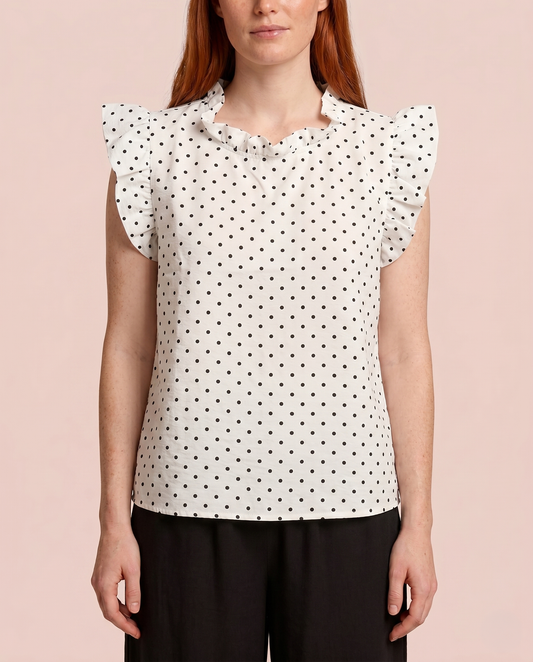 Effortless Ruffle Sleeve Top in Polka Dot Front view of a woman wearing a white blouse with black polka dots and black pants on a beige background