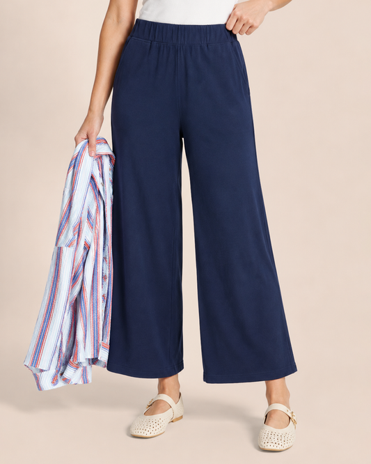 Weekend Ease Wide Leg Crop Pant in Navy Woman wearing navy wide-leg pants, a white tank top, and a striped button-front shirt on a beige background