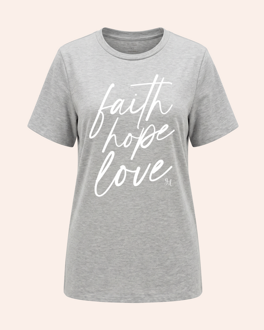 Faith, Hope, Love Girlfriend Tee In Grey Woman wearing a gray t-shirt with 'faith hope love' text and denim shorts on a plain background