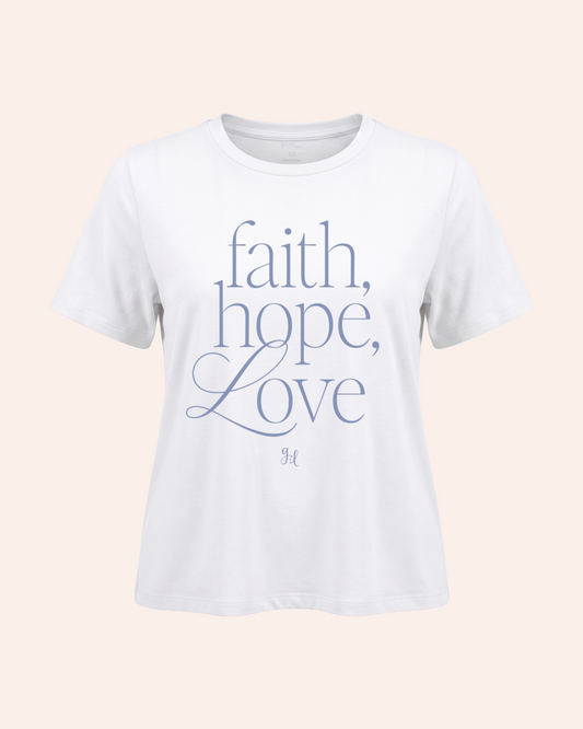 Faith, Hope, Love Vintage Tee in White Model wearing a white t-shirt with 'faith, hope, love' text on a beige background