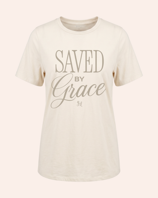 Saved by Grace Girlfriend Tee In Cream Woman wearing a cream t-shirt with 'Saved by Grace' text on a plain background