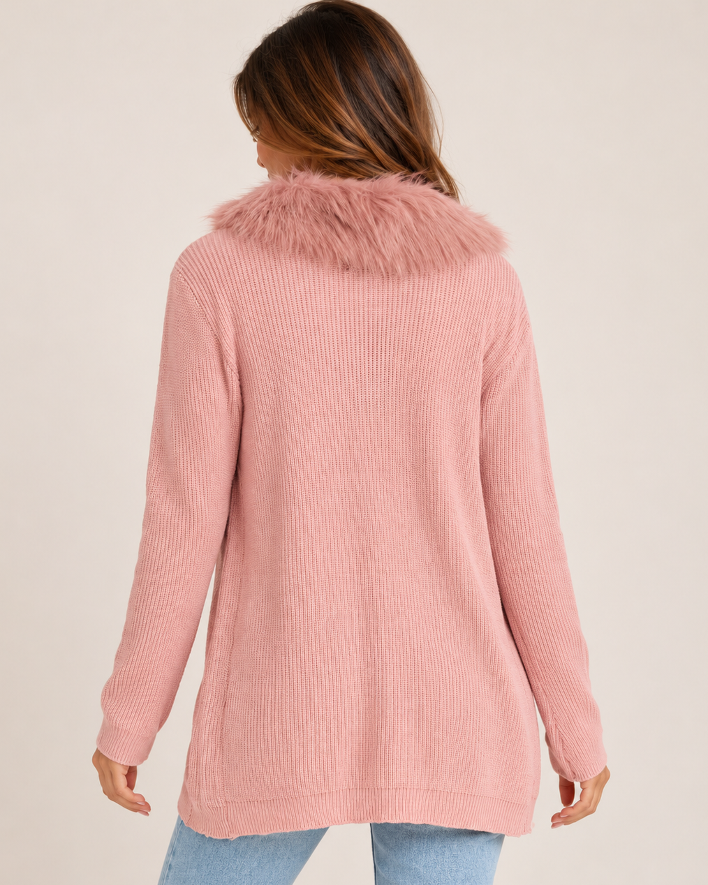 Back view of a woman wearing a blush pink zip-front cardigan with a fluffy faux-fur collar on a beige background.