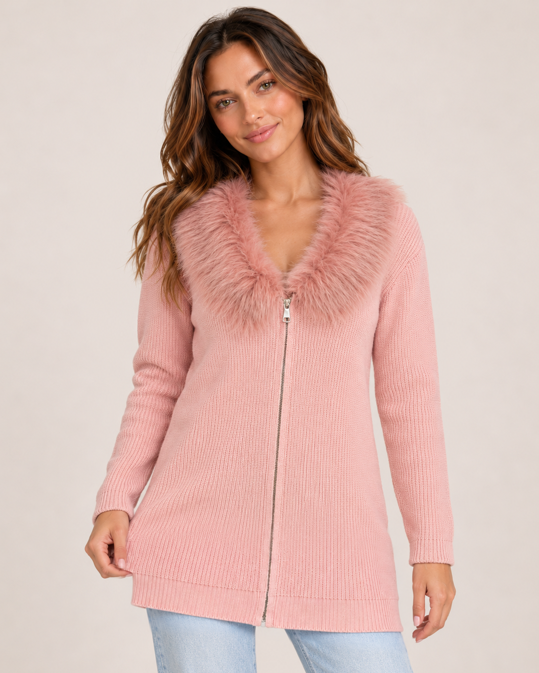 Cropped front view of a woman wearing a blush pink zip-front cardigan with a fluffy faux-fur collar and long sleeves, highlighting the zipper closure and textured trim on a beige background.