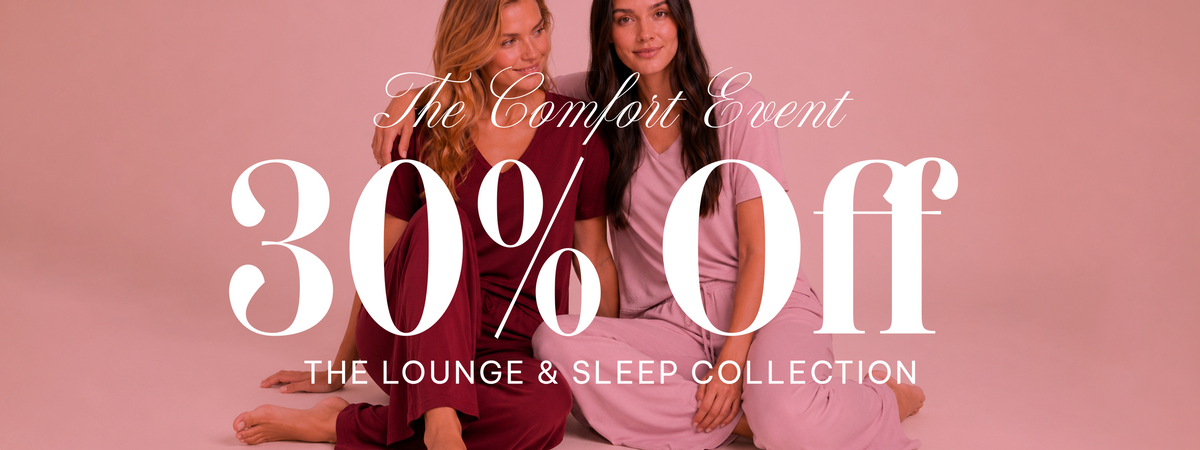 Promotional banner for 'The Comfort Event' featuring two women sitting on a pink studio floor. Large white text reads '30% Off' with 'THE LOUNGE & SLEEP COLLECTION' underneath.