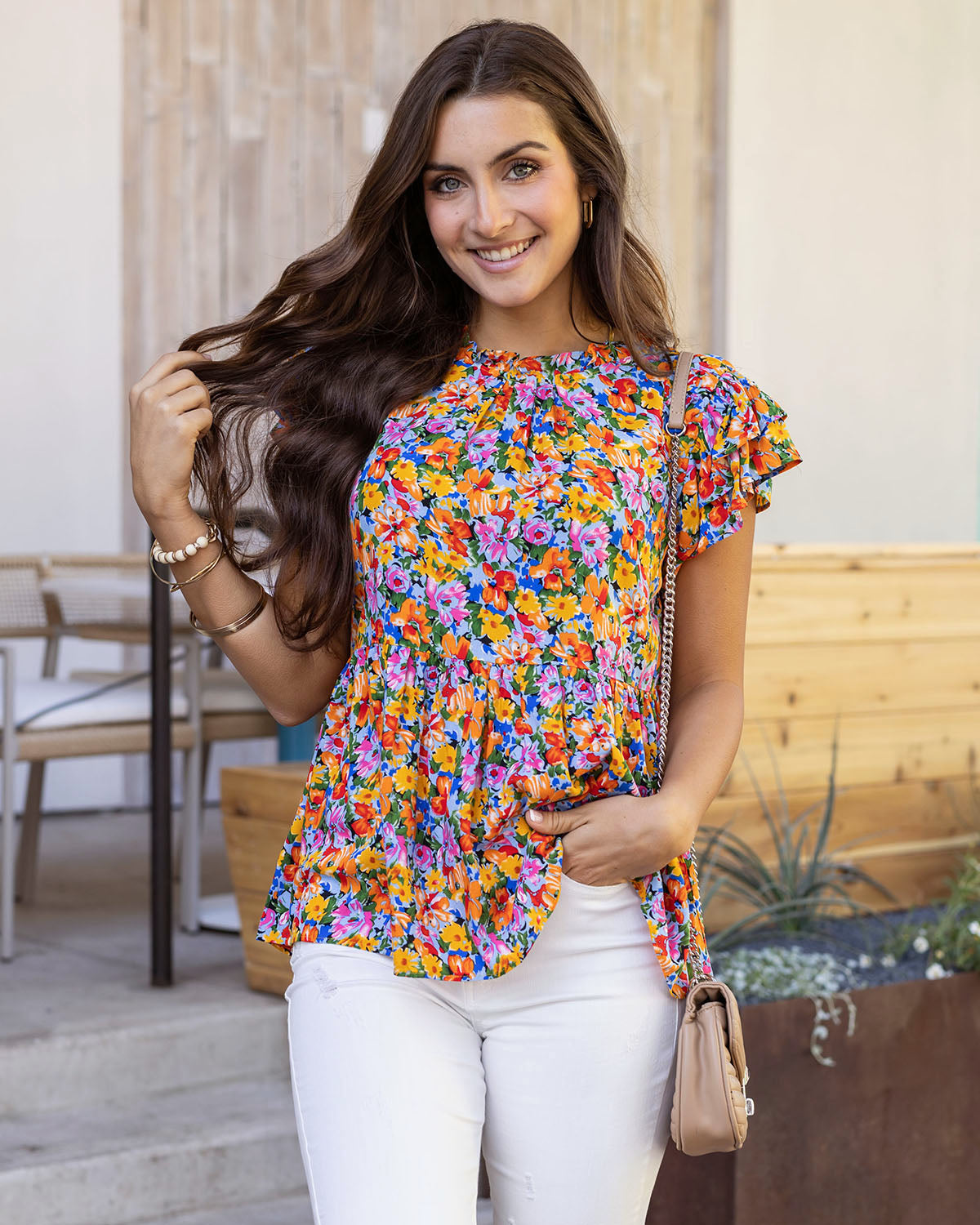 front styled view of freesia floral ruffle sleeve women's blouse styled with handbag and white denim