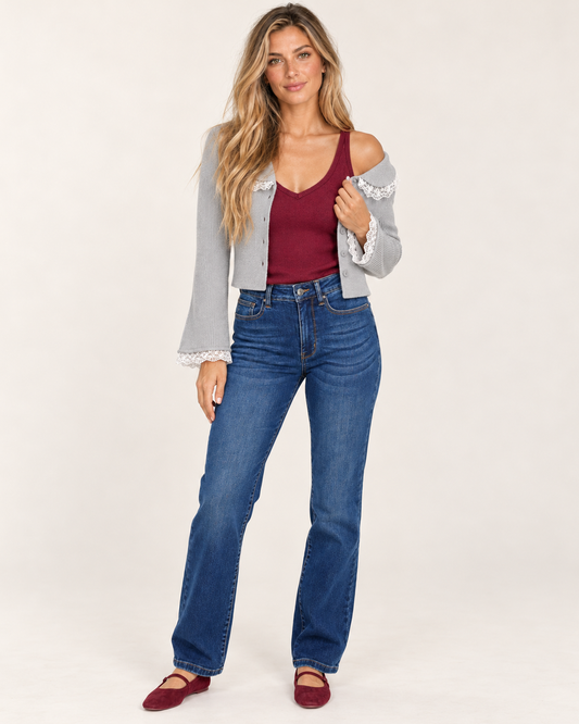 Cropped front view of a woman wearing a burgundy sleeveless V-neck tank top with blue jeans, highlighting the fitted silhouette and neckline on a beige background.