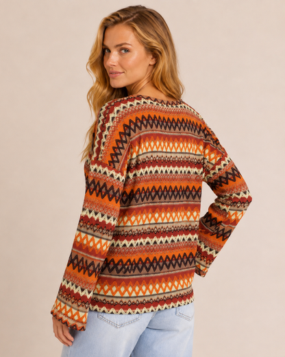 Back view of a woman wearing an orange striped knit pullover sweater with light wash jeans on a beige background