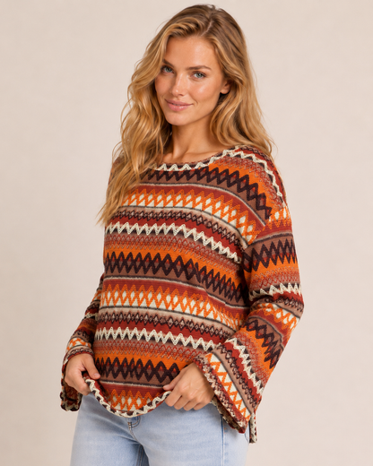 Side View of a woman wearing an orange striped knit pullover sweater with light wash jeans on a beige background