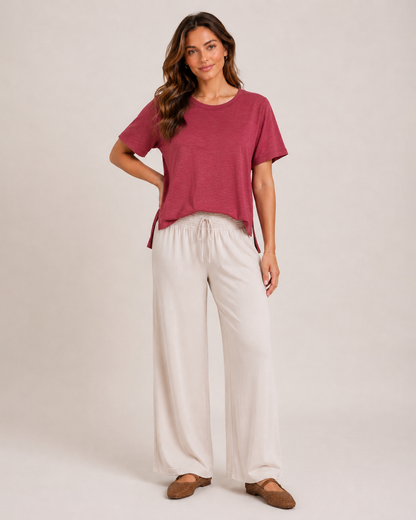 Full-body view of a woman wearing a Berry Ice cotton slub tee with white wide-leg pants and white shoes on a beige background