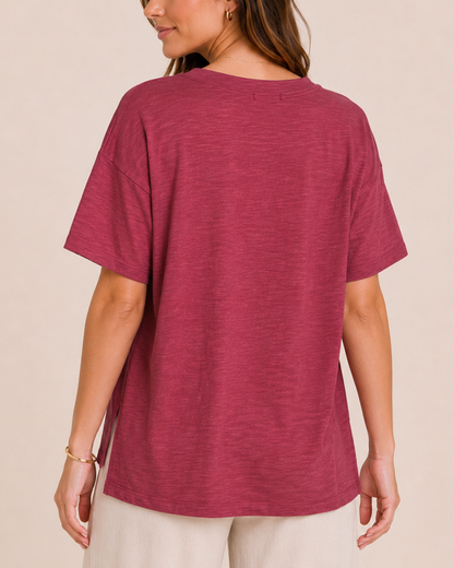 Back view of a woman wearing a Berry Ice cotton slub tee with white wide-leg pants on a beige background