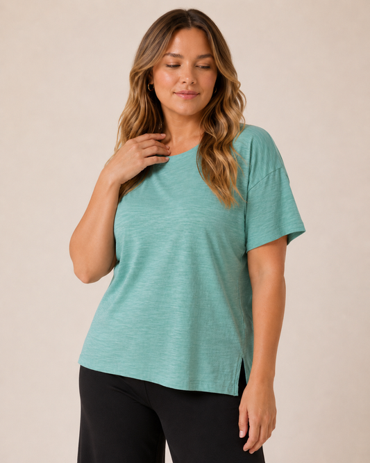 Close-up front view of a woman wearing a Sagebrush cotton slub tee with black pants  on a beige background