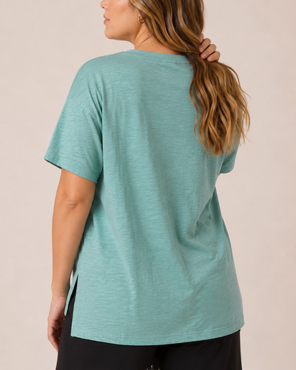 Back view of a woman wearing a Sagebrush cotton slub tee with black pants on a beige background