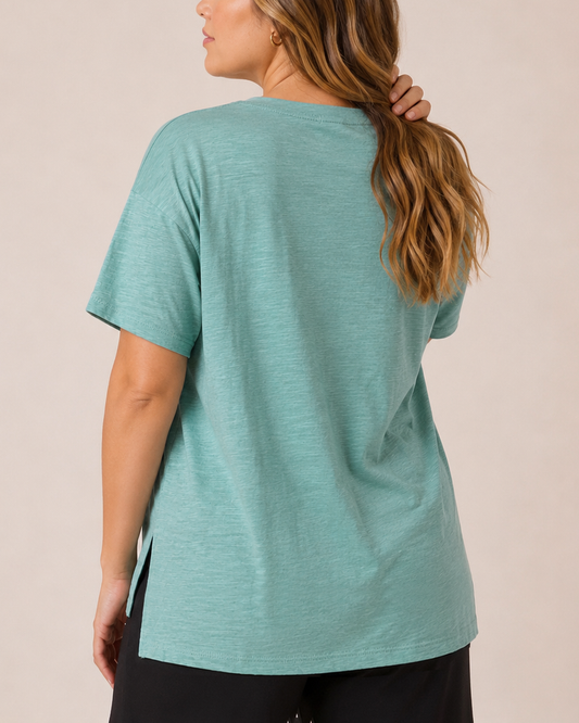 Close-up front view of a woman wearing a Sagebrush cotton slub tee with black pants  on a beige background