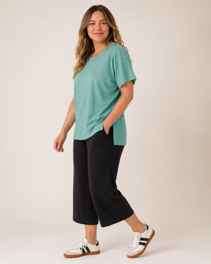 Side view of a woman wearing a Sagebrush cotton slub tee with black pants on a beige background