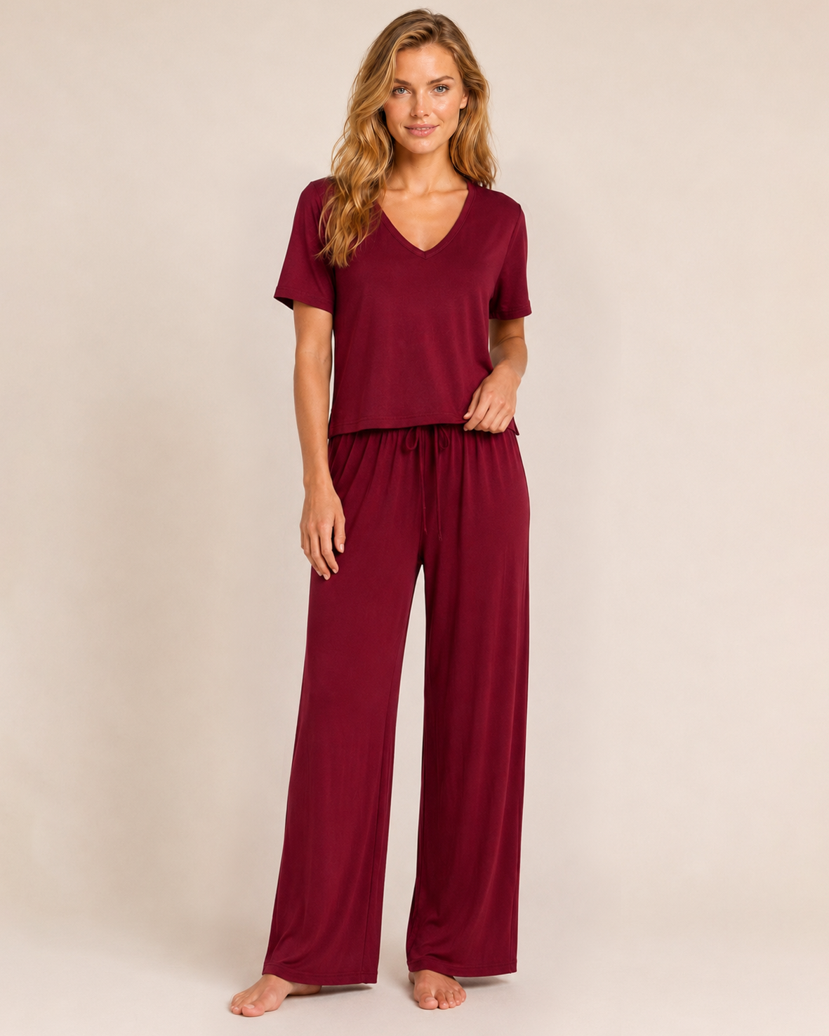 Full-body view of a woman wearing cabernet wide-leg pajama pants with a matching top on a beige background