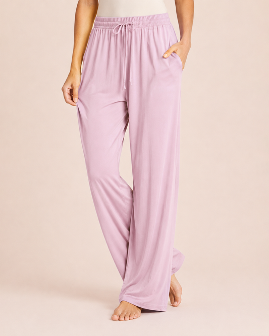 Close up-body view of a woman wearing Mauve Mist wide-leg pajama pants on a beige background