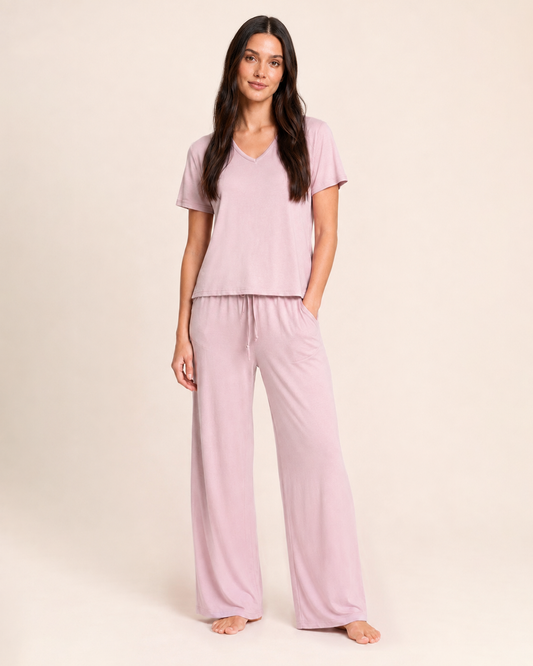 Close up-body view of a woman wearing Mauve Mist wide-leg pajama pants on a beige background