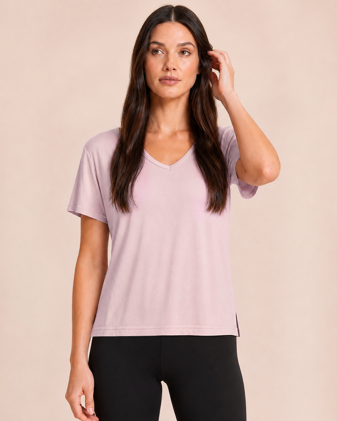 Close up view of a woman wearing a Mauve Mist V-neck pajama top with black pants on a beige background