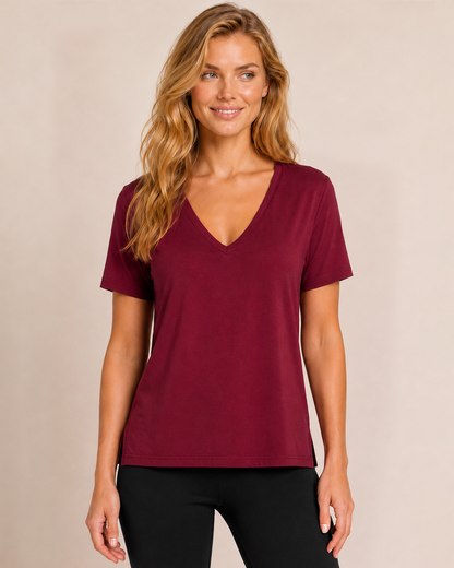 Close up front view of a woman wearing a cabernet V-neck pajama top with matching wide-leg pants on a beige background
