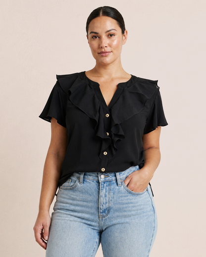 Elegant Easy Button Blouse in Black tucked in to denim blue jeans.
