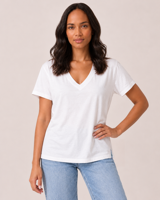 Cropped front view of a woman wearing a white V-neck short-sleeve T-shirt with light-wash jeans, highlighting the relaxed fit and neckline on a beige background.