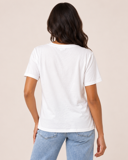 Back view of a woman wearing a white V-neck short-sleeve T-shirt with light-wash jeans on a beige background.