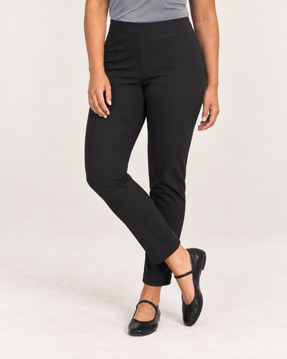Cropped front view of a woman wearing black ankle-length leggings with a wide waistband and black Mary Jane shoes on a beige background