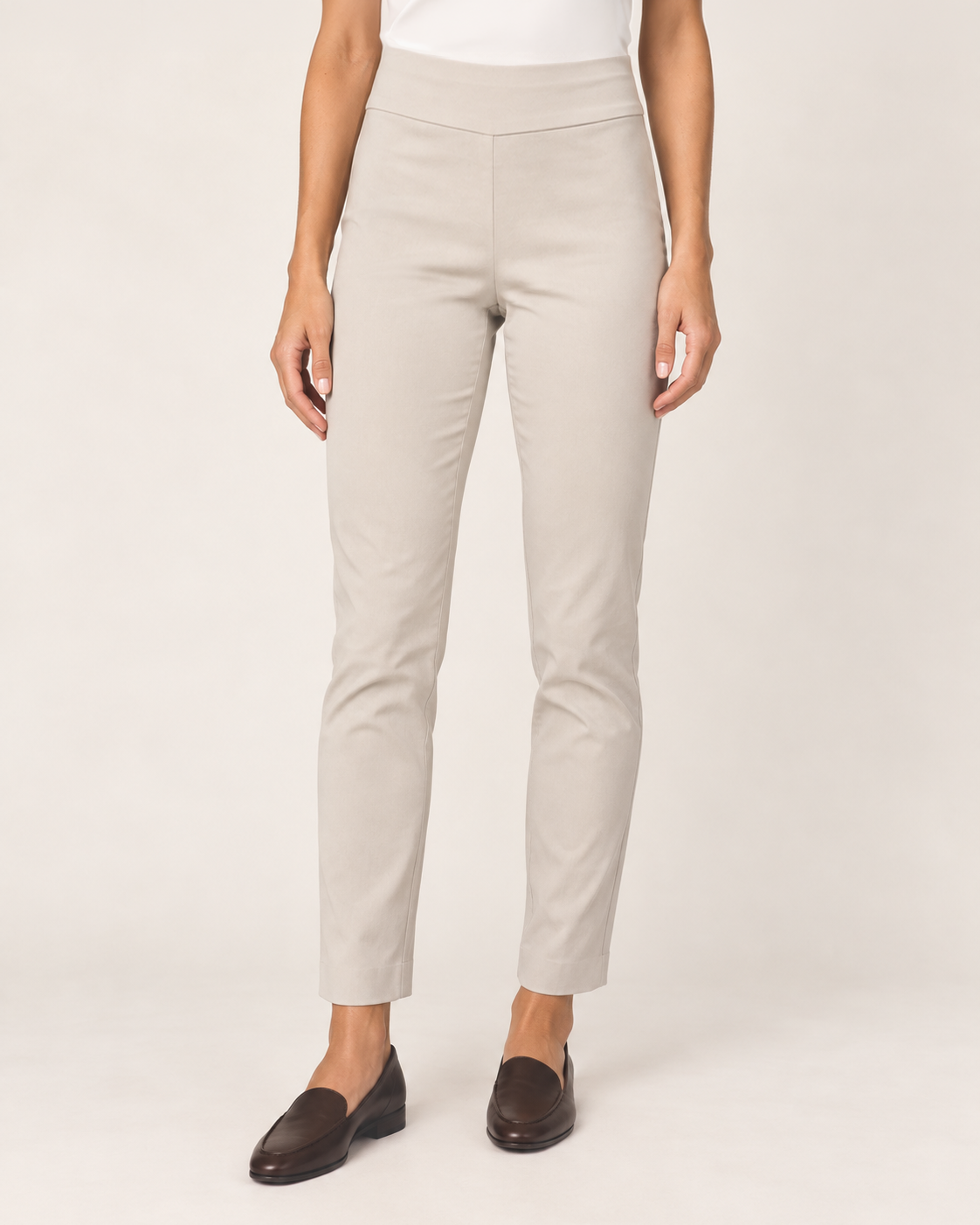 Front view of tan ponte pants with a tapered leg and black loafers on a beige background