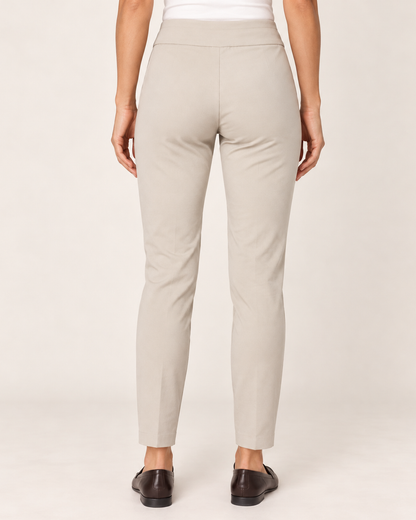  Back view of a woman wearing tan ponte pants with black loafers on a beige background