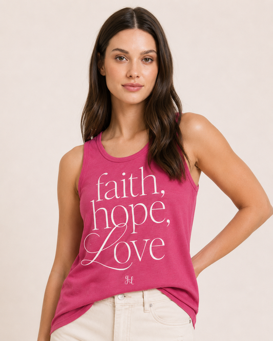 Close-up of a woman wearing a pink graphic tank top featuring a "Faith, Hope, Love" inspirational design and natural shorts on a beige background