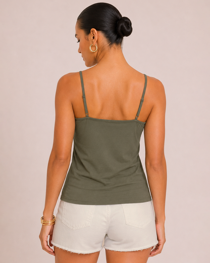Back view of a woman wearing an olive green spaghetti strap tank top and white shorts on a beige background