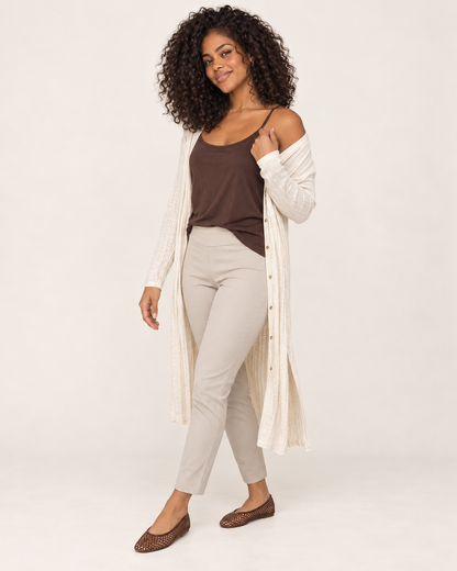 Full-body side view of a woman wearing a brown spaghetti-strap tank top with white wide-leg pants and white sneakers on a beige background
