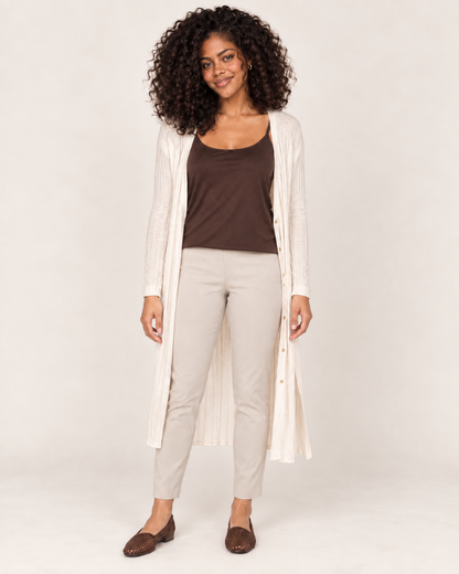 Full-body front view of a woman wearing a brown spaghetti-strap tank top with white wide-leg pants and white sneakers on a beige background