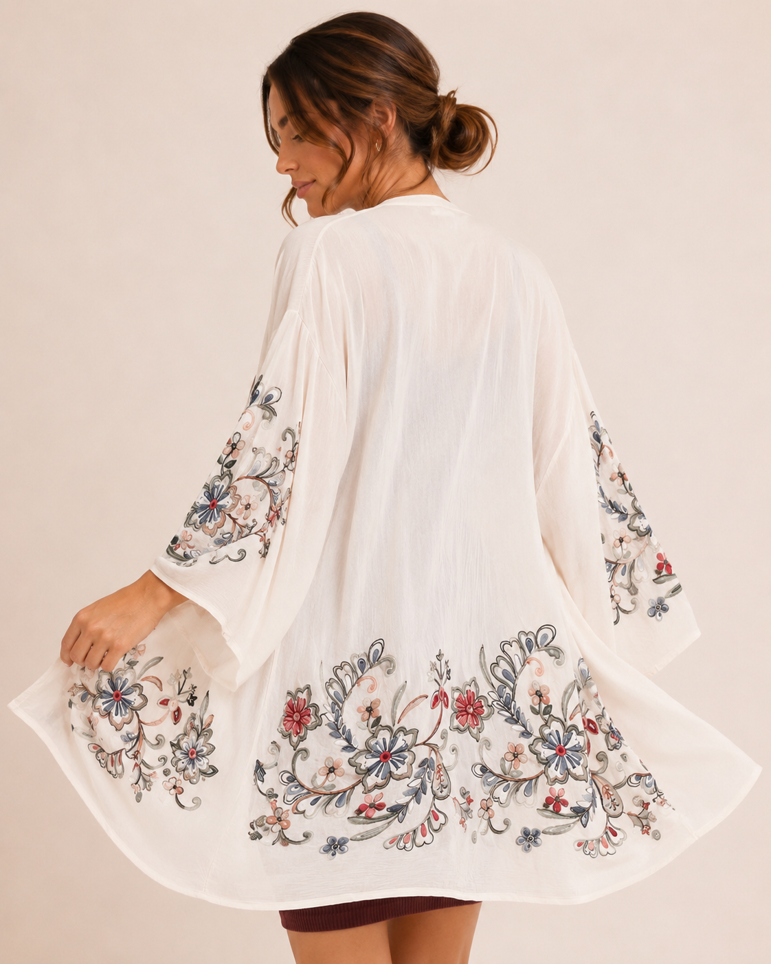 Back view of a woman wearing a cream floral kimono over a burgundy ribbed tank dress on a beige background
