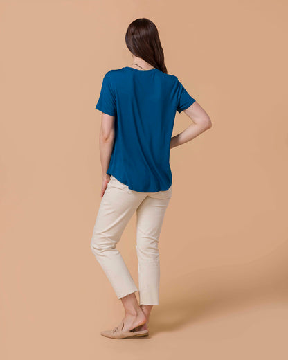 Woman sitting wearing Perfect Fit V-Neck Pocket Tee - Teal and natural colored distressed denim back view