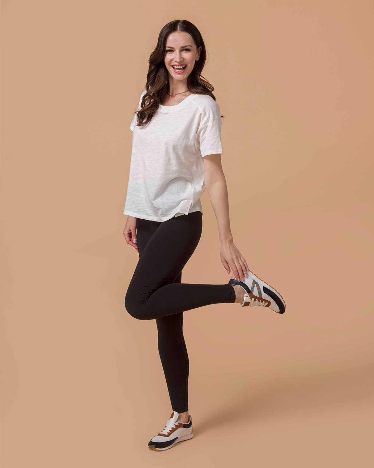 Woman wearing a The Essential Cotton Slub Tee - White and black leggings on a beige background