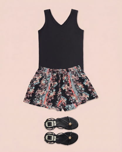 Black sleeveless top paired with floral print shorts on a beige background