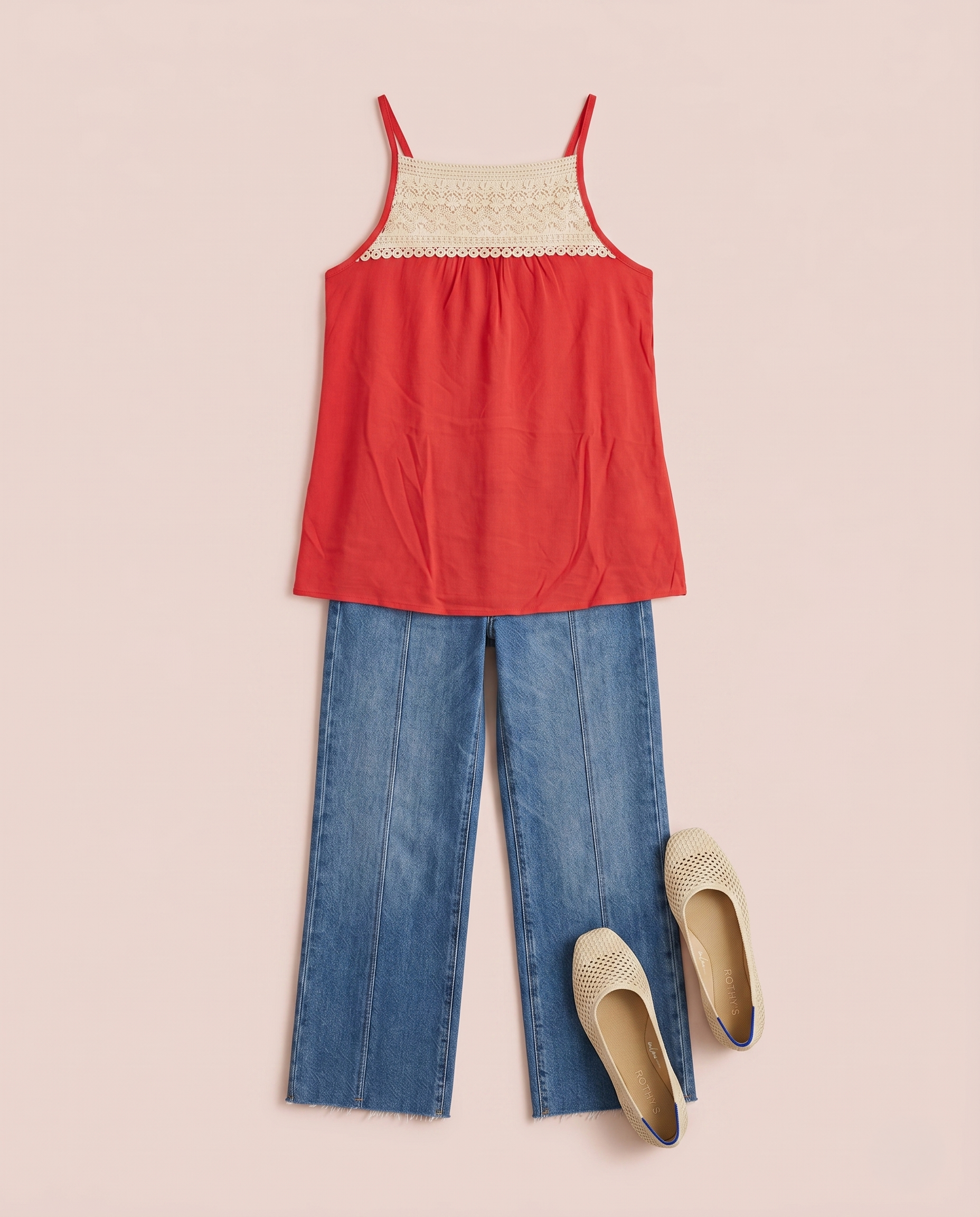 Coral camisole top with a crochet lace yoke styled with blue jeans on a beige background