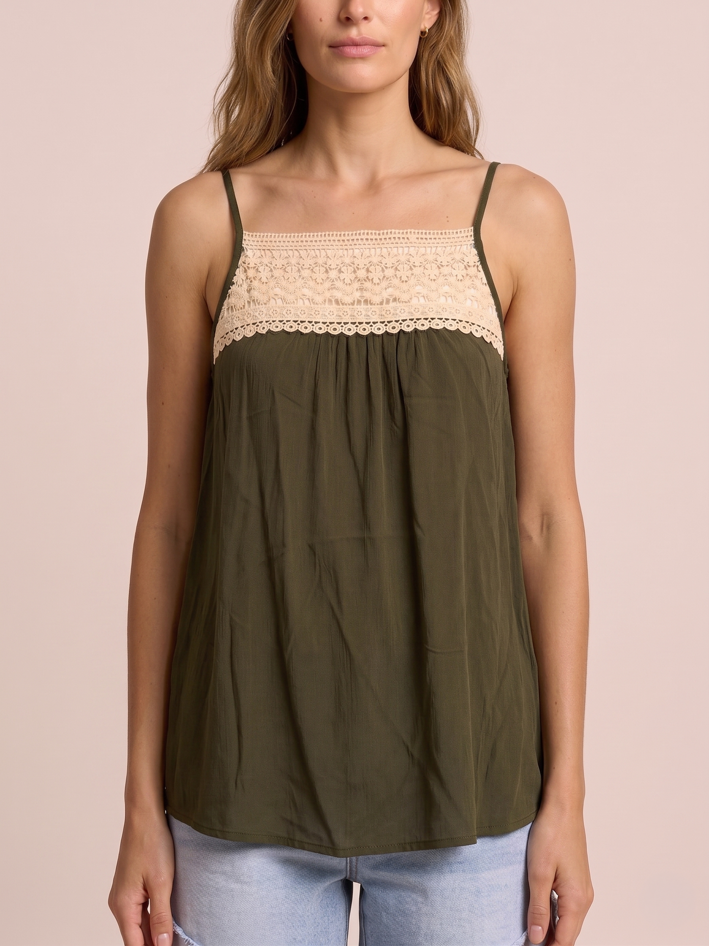 Close-up of a woman in an olive green tank top featuring lace trim and adjustable spaghetti straps on a beige background