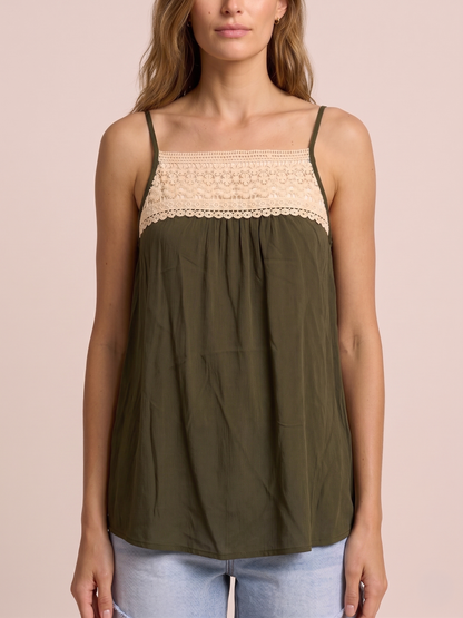 Close-up of a woman in an olive green tank top featuring lace trim and adjustable spaghetti straps on a beige background