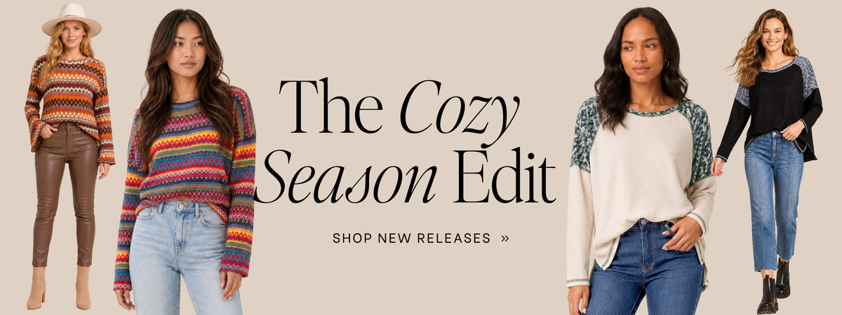 A promotional banner for 'The Cozy Season Edit' featuring four female models showcasing different cozy sweaters and outfits against a solid beige background. The text 'The Cozy Season Edit' and 'SHOP NEW RELEASES >>' is displayed in the center.