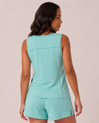 Back view of a woman wearing a capri blue tank top with black leggings on a beige background