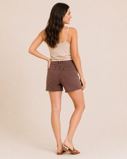 Back view of a woman wearing wine distressed shorts, a beige sleeveless top, and a multicolored plaid shirt on a beige background