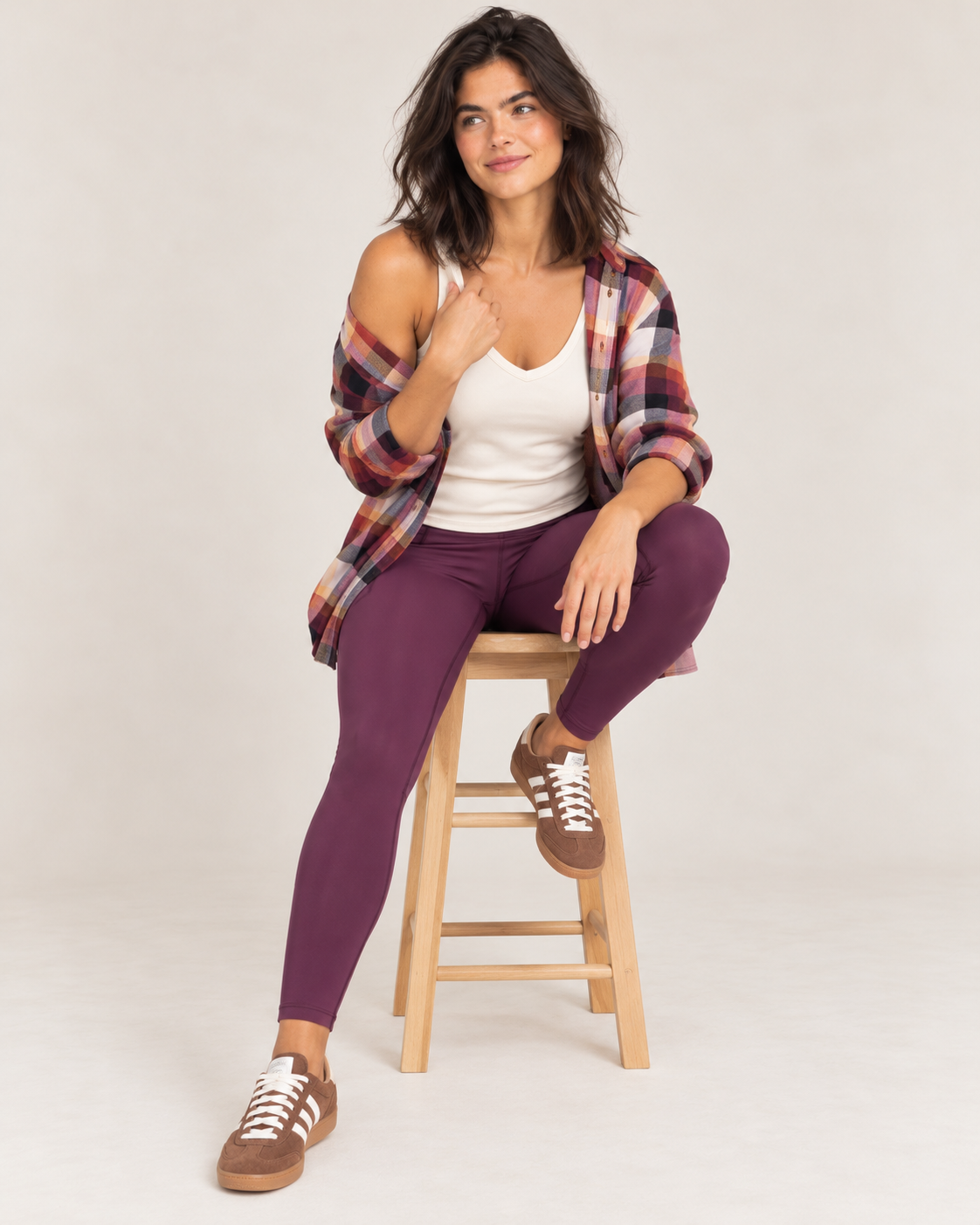 Model wearing soft sculpt bran tank, plum soft sculpt leggings and plaid top sitting on a stool