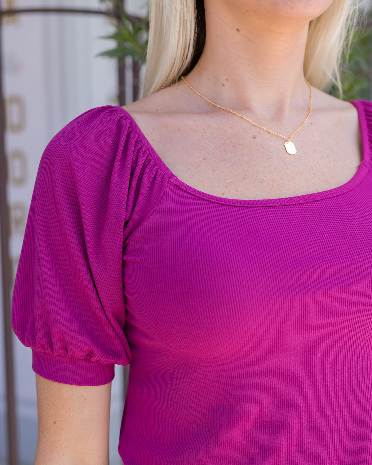 Close up view of sleeve on magenta ribbed knit top