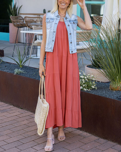 Front view of light-wash denim vest paired with maxi dress and straw tote