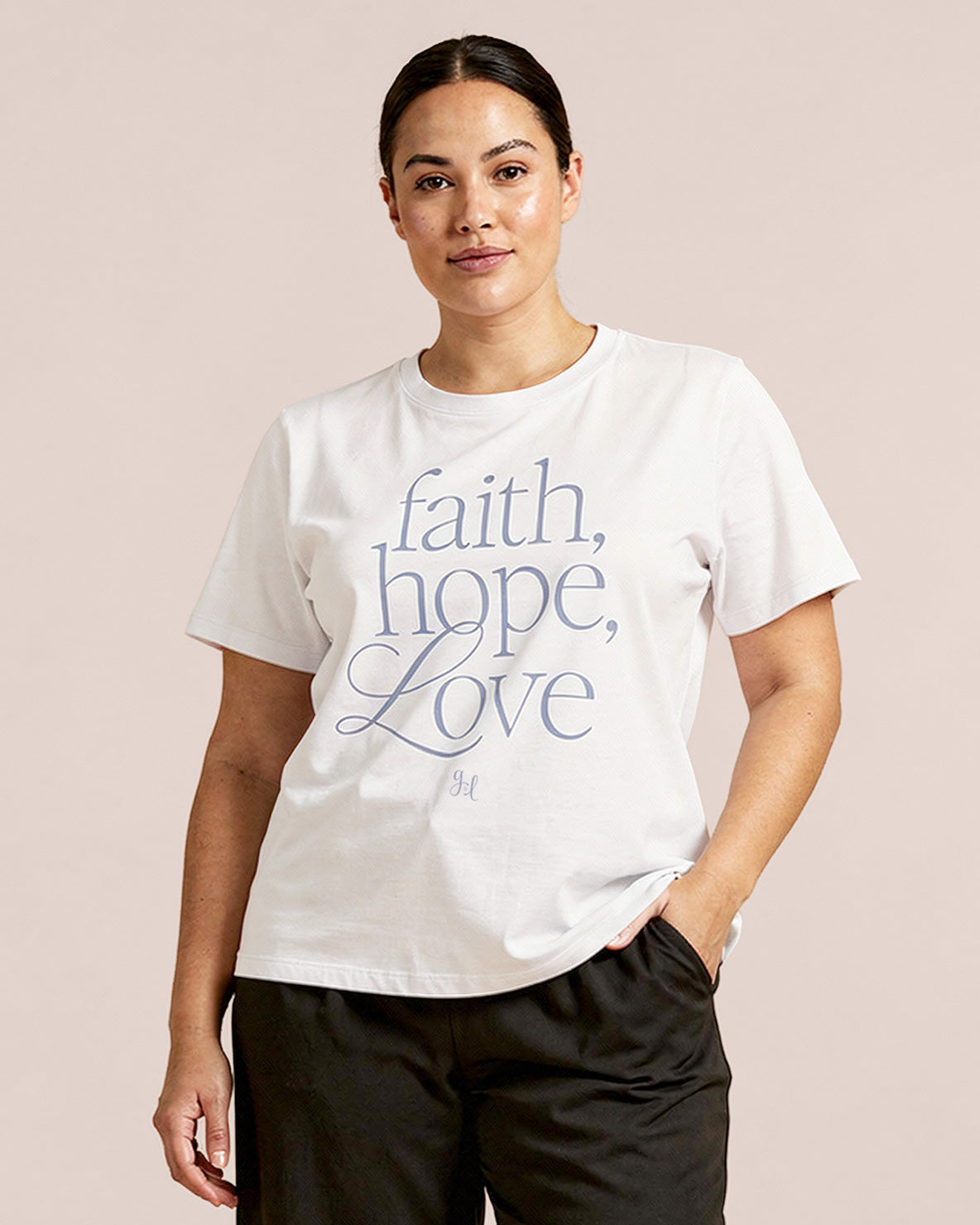 Model wearing a white t-shirt with 'faith, hope, love' text on a beige background