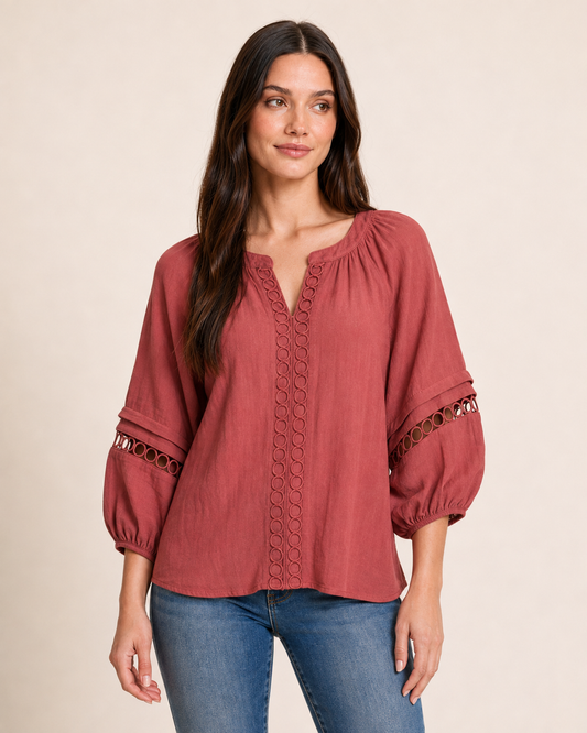 Front view of a warm rust-red textured knit top with balloon sleeves on a beige background